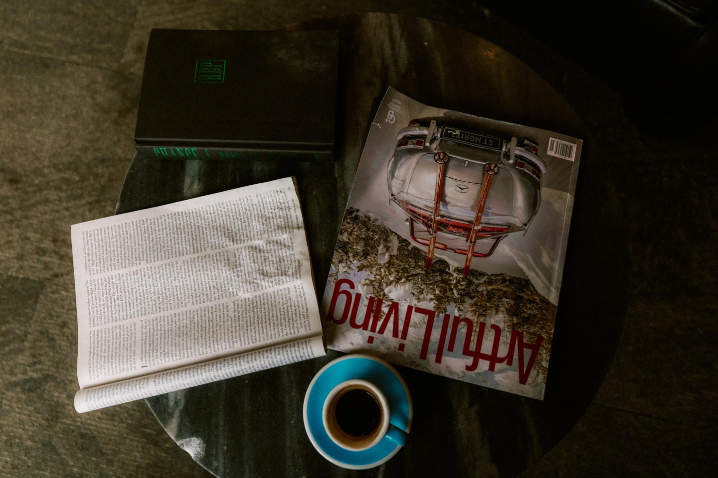 A laptop, magazine, newspaper, and coffee on a table.