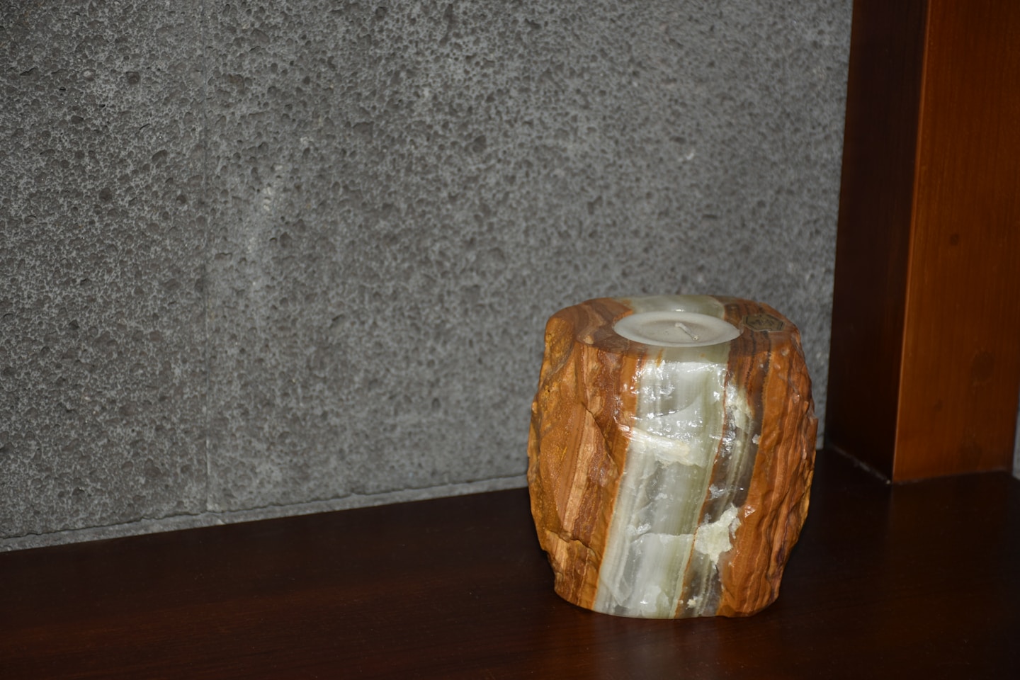 Rough-hewn stone candle holder on dark wood surface