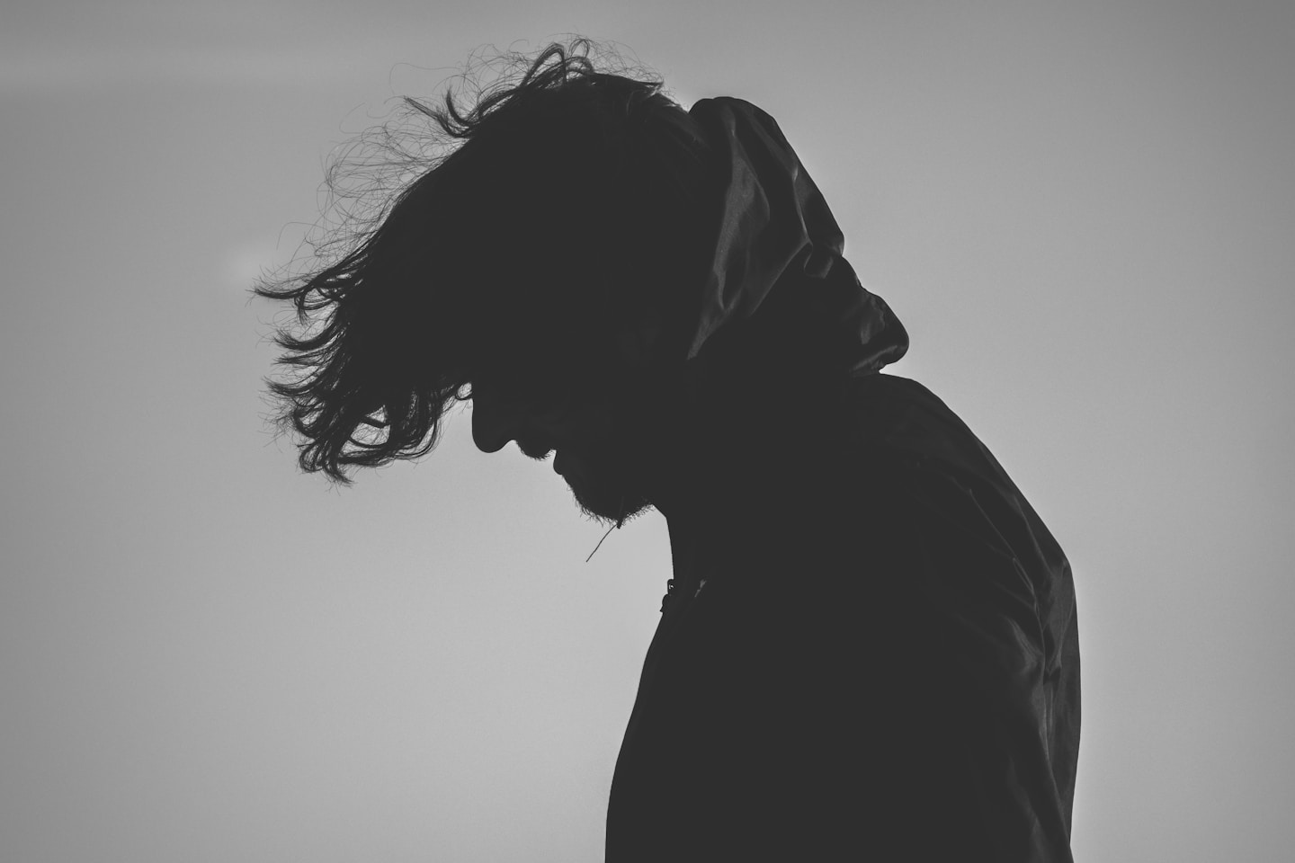 silhouette of man wearing hoodie looking down