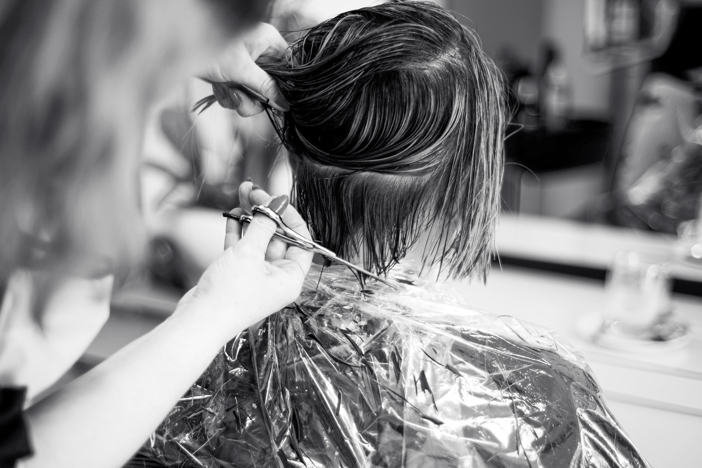 a woman cutting another woman's hair in a salon